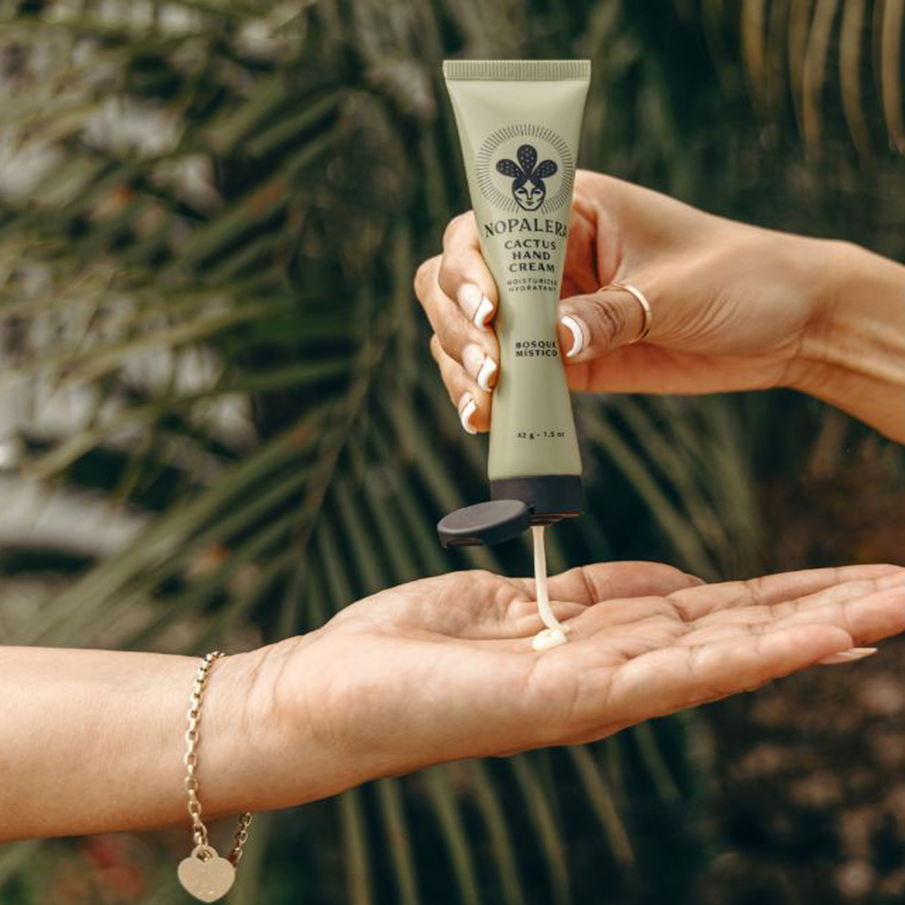 Innovate the Label Nopalera hand cream being squeezed from tube onto hand outdoors with blurred greenery background