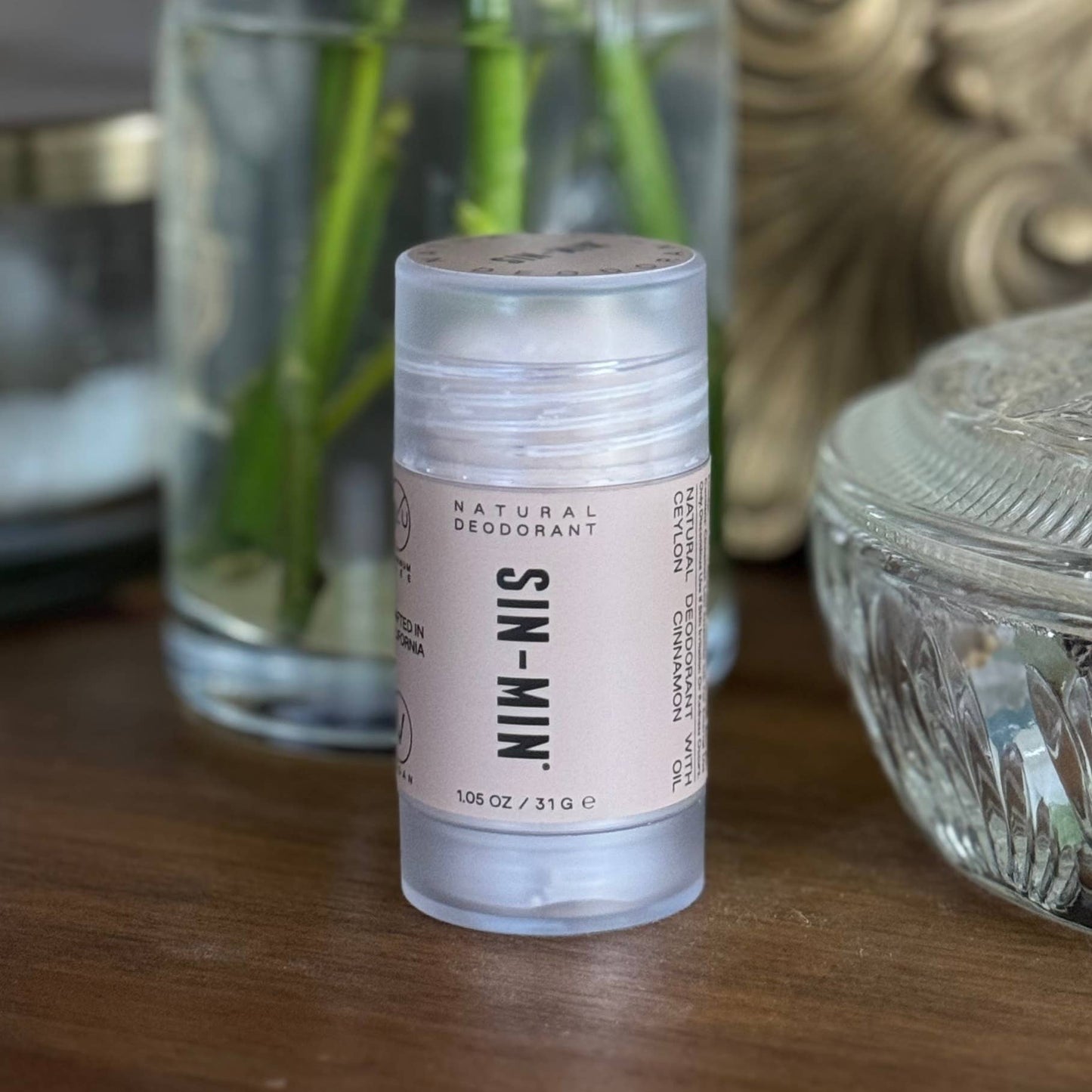 SIN-MIN natural travel size deodorant stick with light pink label on wooden surface