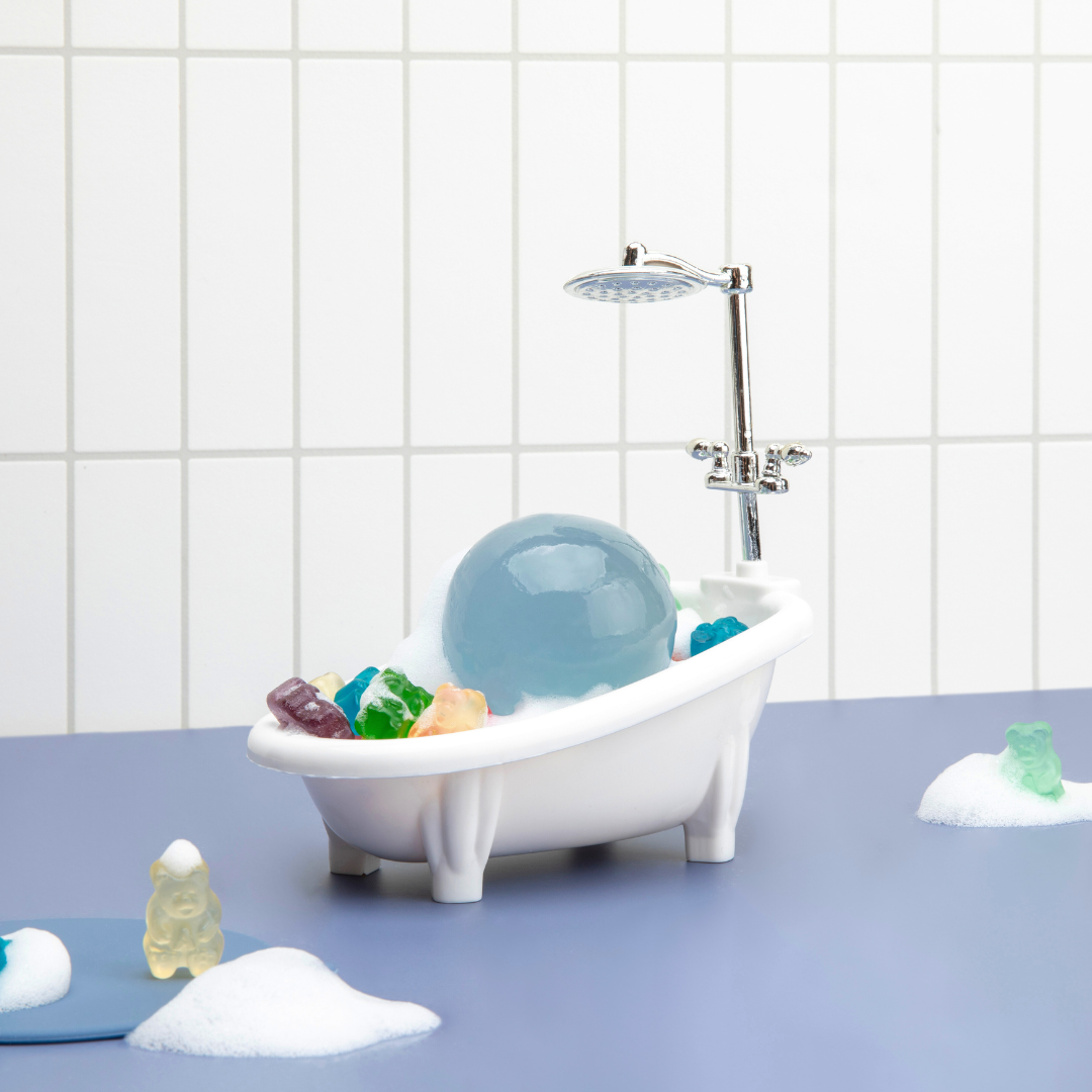 Naisture aqua jelly ball cleanser displayed in white miniature bathtub with blue jelly ball and foam