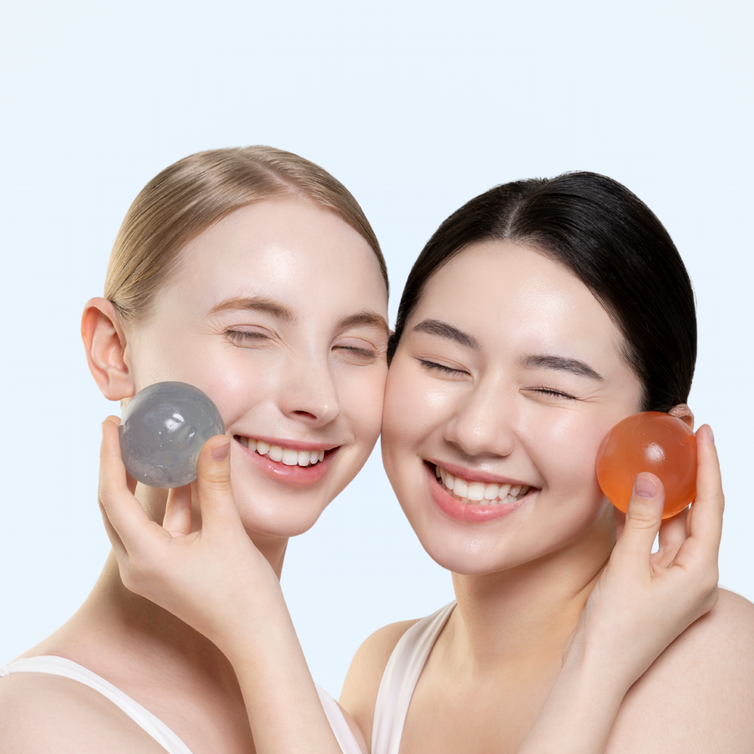 Naisture aqua jelly ball cleanser displayed by two smiling women holding gray and orange cleansing jelly balls to cheeks