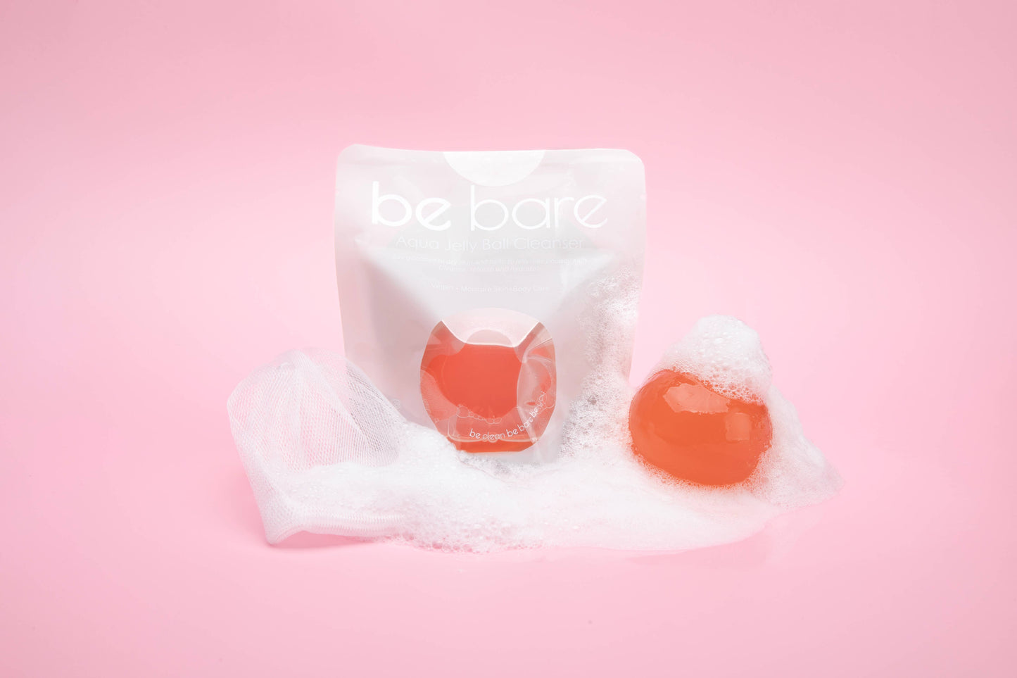 aqua jelly ball cleanser by Naisture shown with orange jelly ball foam and pouch on pink background