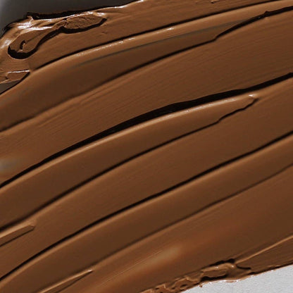 Close-up of smooth creamy brown cream bronzer for face swatched on white background
