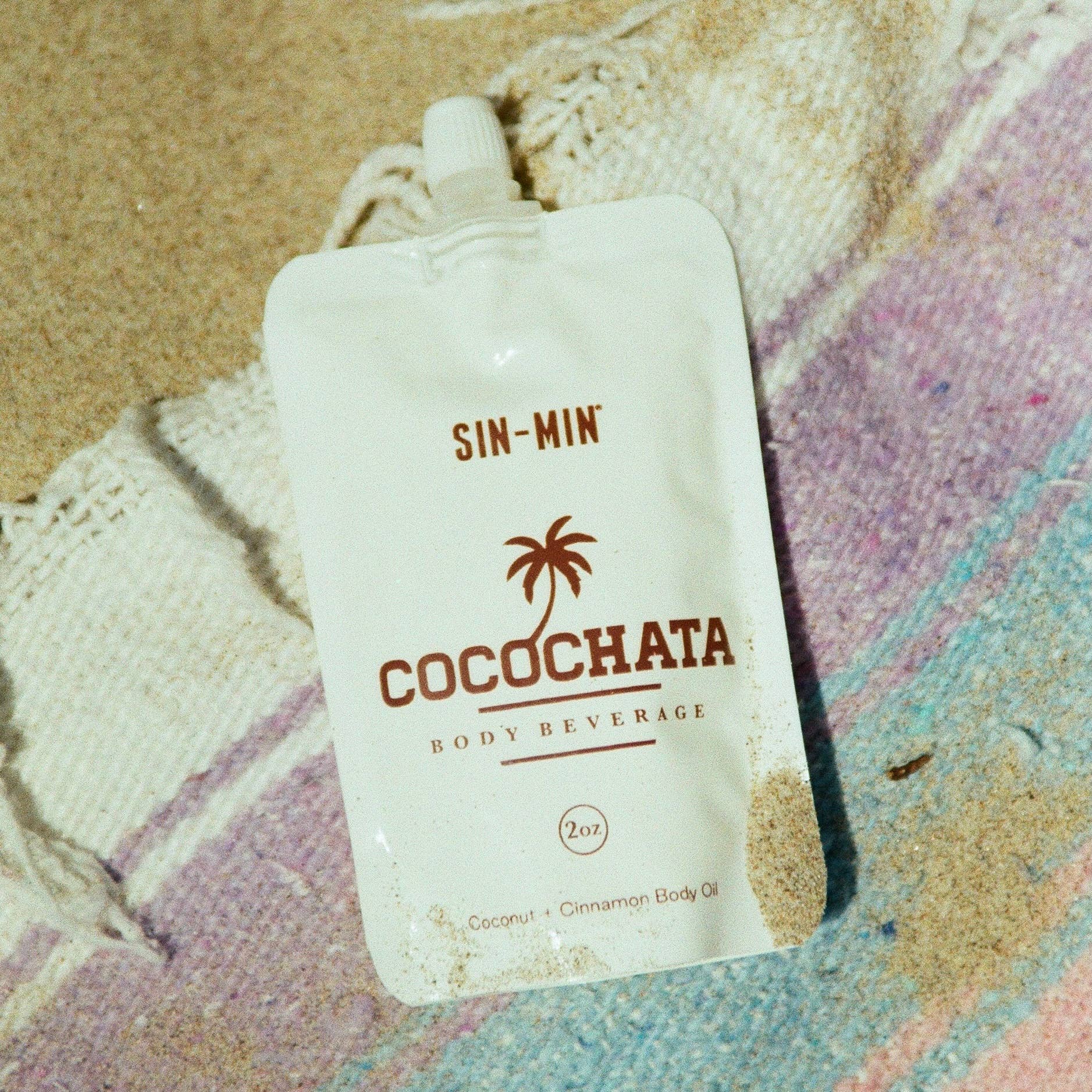 SIN-MIN cocochata coconut oil cinnamon body lotion pouch on colorful sandy surface