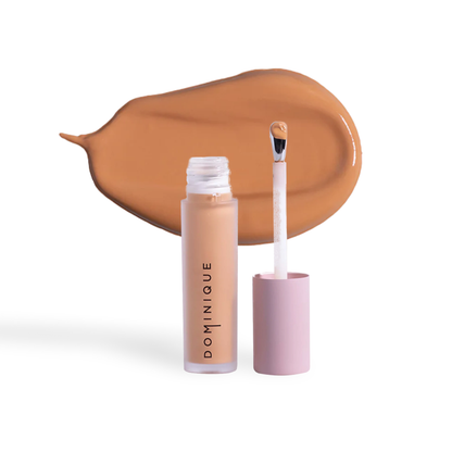 Dominique Cosmetics concealer in a beige shade with applicator and swatch on white background
