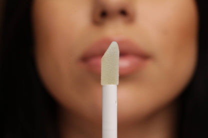 Innovate the Label light pink nude lip gloss applicator close to lips for smooth glossy finish