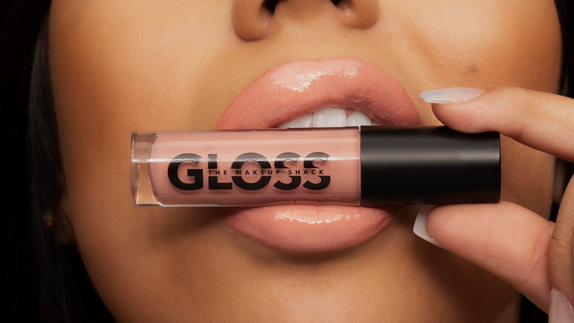 Innovate the Label light pink nude lip gloss held near lips showing glossy smooth color finish