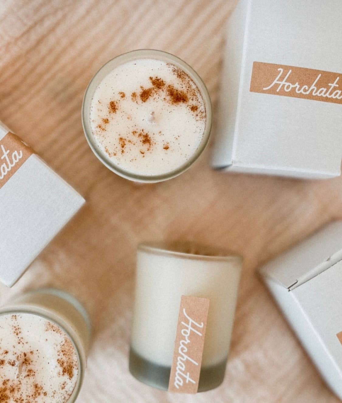 SIN-MIN horchata candle in frosted glass with cinnamon topping and white packaging boxes
