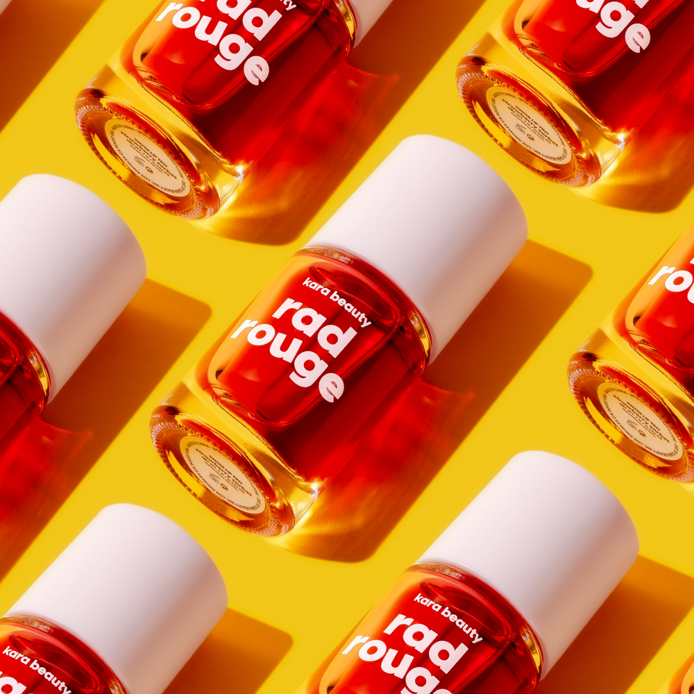 Kara Beauty Rad Rouge Lip Tint in red with white cap displayed on yellow background