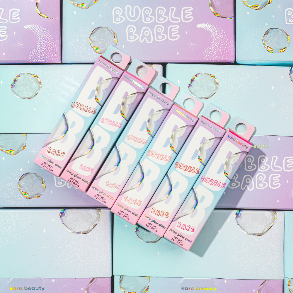 Kara Beauty Bubble Babe strawberry gloss stick boxed pastel packaging arranged on matching pastel bubble background
