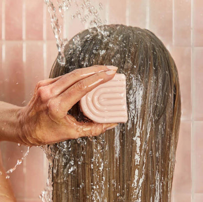 Innovate the Label castor oil conditioner bar being applied to wet hair under running water in shower