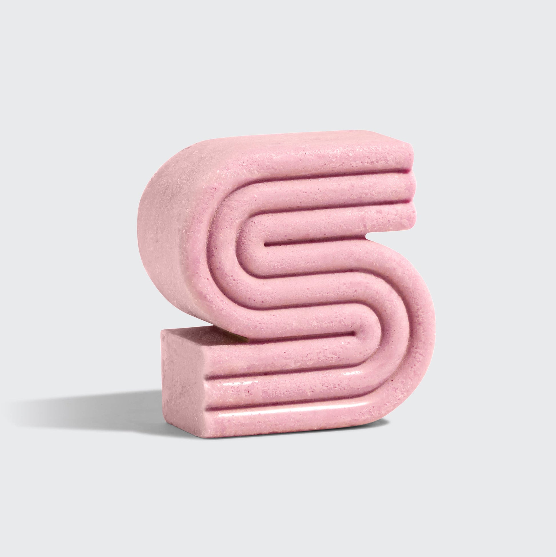 Innovate the Label pink castor oil shampoo bar with unique spiral design on gray background