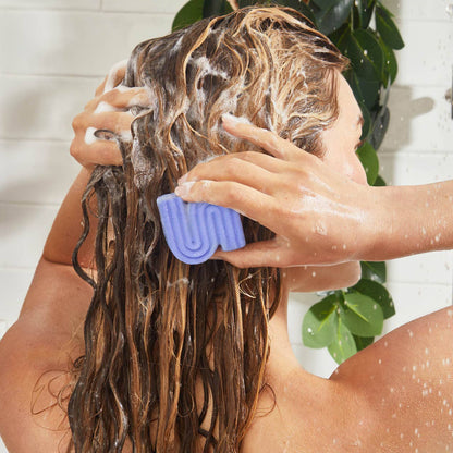 Person washing blonde hair with purple shampoo bar for blonde hair in shower with lather