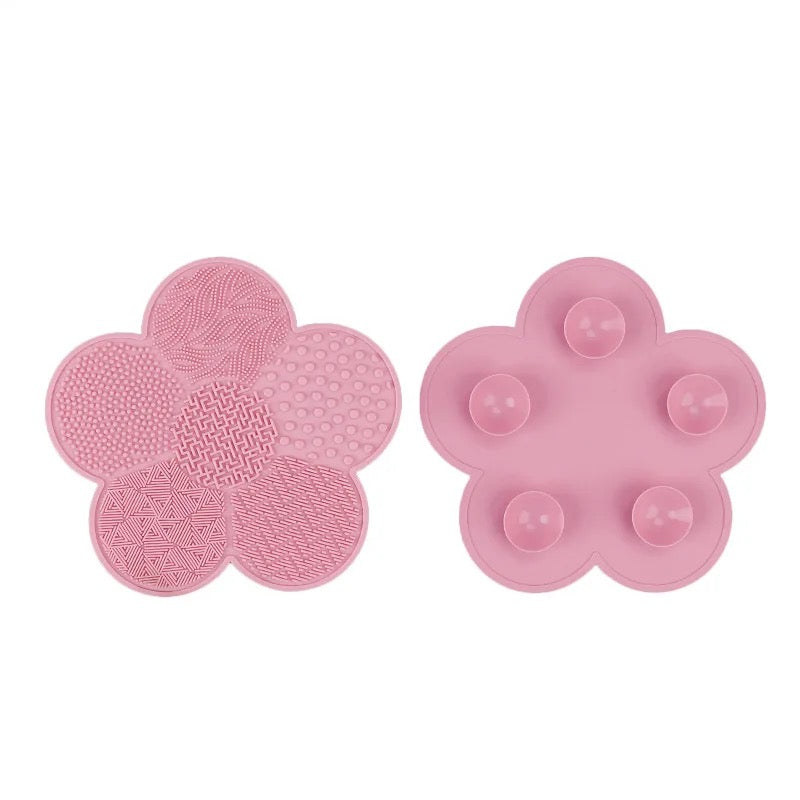 Pink flower-shaped silicone makeup brush cleaning mat with textured surface and suction cup backing