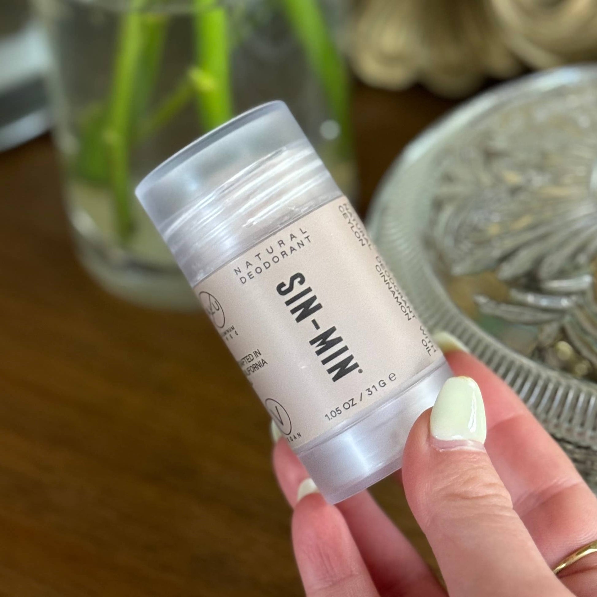 SIN-MIN natural travel size deodorant stick held in hand with clear cap and beige label